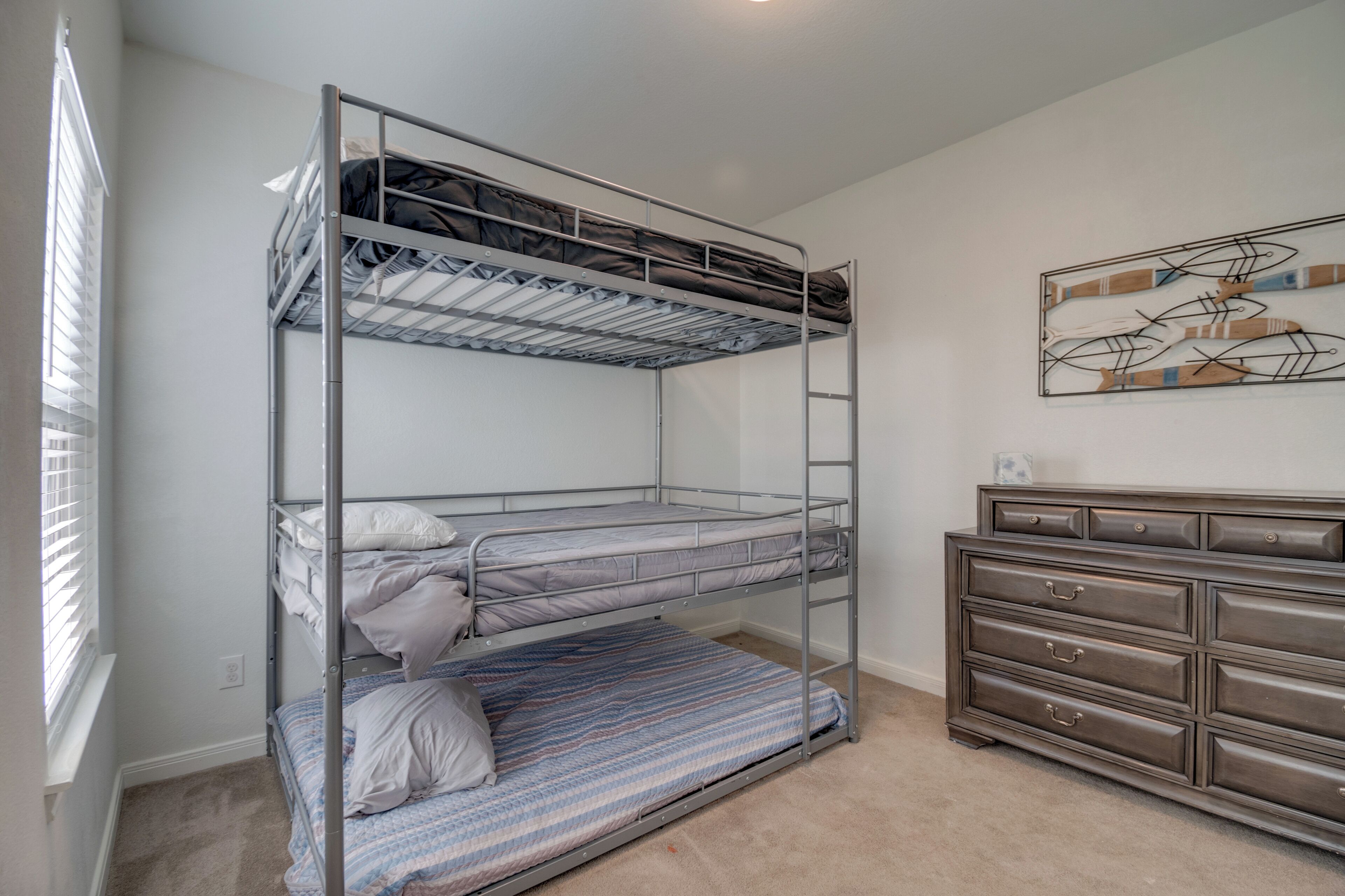 A bunk bed with a dresser and a wall art piece.