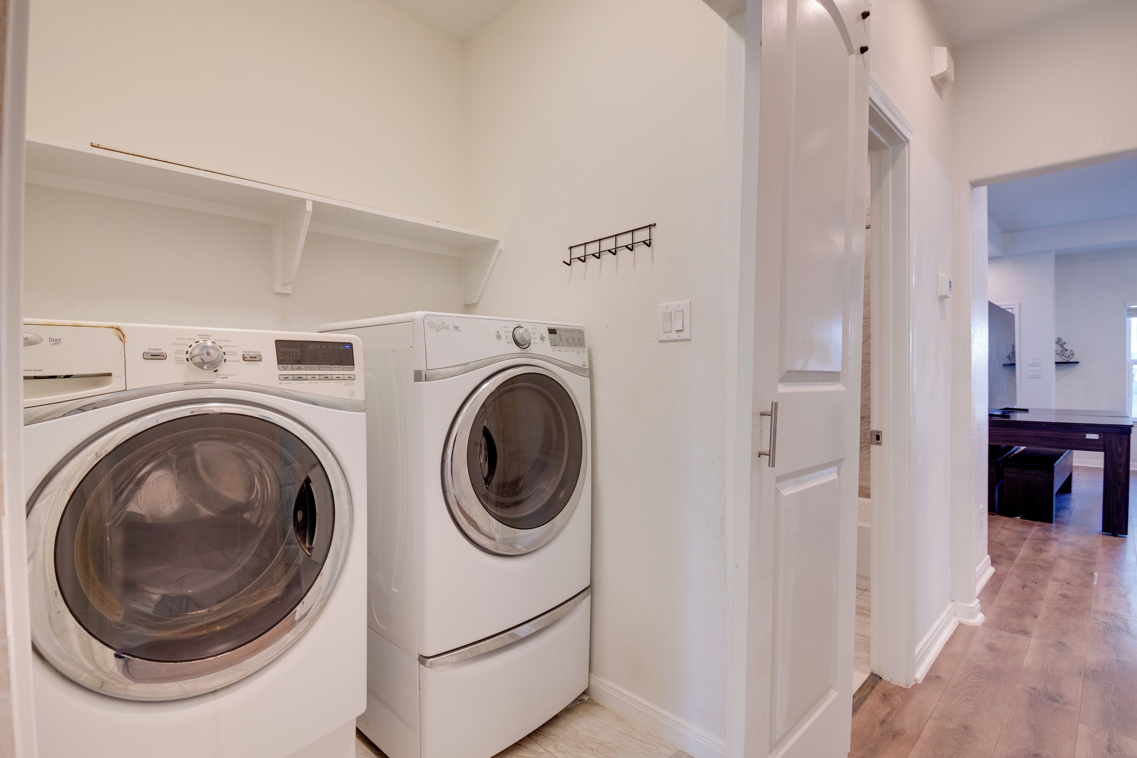 A laundry room with two front-loading washing machines and a drying rack.