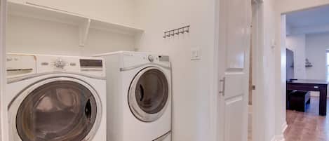 A laundry room with two front-loading washing machines and a drying rack.