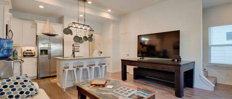 A modern kitchen with white cabinets, a stainless steel refrigerator, and a hanging pot rack.