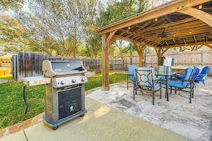 Une terrasse extérieure équipée d’un barbecue, de chaises et d’une pergola.