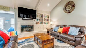 A living room with a fireplace, a leather sofa, a coffee table, and a bookshelf. - Outdoor Entertainment Space: Austin Family Home (Austin)