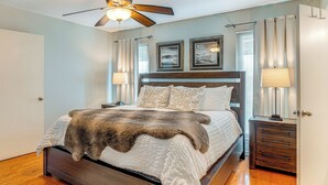 A bedroom with a bed, wooden headboard, two bedside tables with lamps, a ceiling fan, and a window with curtains. - Outdoor Entertainment Space: Austin Family Home (Austin)