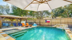 A backyard with a swimming pool, lounge chairs, and a covered patio area. - Outdoor Entertainment Space: Austin Family Home (Austin)