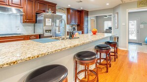 A kitchen with wooden cabinets, stainless steel appliances, a granite countertop, and bar stools. - Outdoor Entertainment Space: Austin Family Home (Austin)