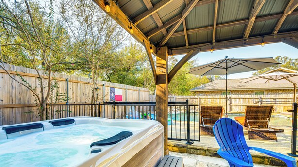 A hot tub under a wooden pergola with wicker chairs and an umbrella. - Outdoor Entertainment Space: Austin Family Home (Austin)