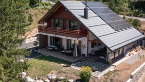 A modern two-story house with a sloped roof, solar panels, and a balcony with outdoor furniture. - Holiday Home Aria (Ravna Gora)