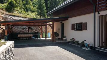 A covered outdoor area with a bench, a barbecue grill, and a stone wall.
