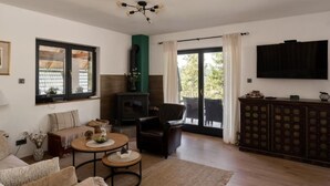 A living room with a fireplace, a sofa, a coffee table, and a TV mounted on the wall. - Holiday Home Aria (Ravna Gora)