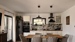 A modern kitchen with a central island, pendant lighting, and a view of the outdoors. - Holiday Home Aria (Ravna Gora)