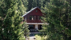 A cabin surrounded by dense forest, with a balcony and outdoor seating area. - Holiday Home Aria (Ravna Gora)