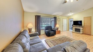 A living room with a sectional sofa, a fireplace, a television, and a ceiling fan. - 8 Mi to Bonners Ferry: Quiet Getaway w/ Patio (Moyie Springs)