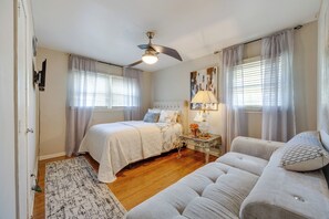 Ein Schlafzimmer mit einem Bett, einem Nachttisch mit Lampe, einem Sofa und einem Deckenventilator.