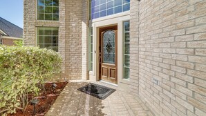A brick building with a wooden door, green shutters, and a window with a grid pattern. - Lake-view Home w/ Pool Access in Legends Ranch! (Spring)
