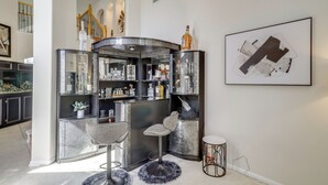 A corner bar area with a marble countertop, two bar stools, and a variety of bottles and glasses. - Lake-view Home w/ Pool Access in Legends Ranch! (Spring)