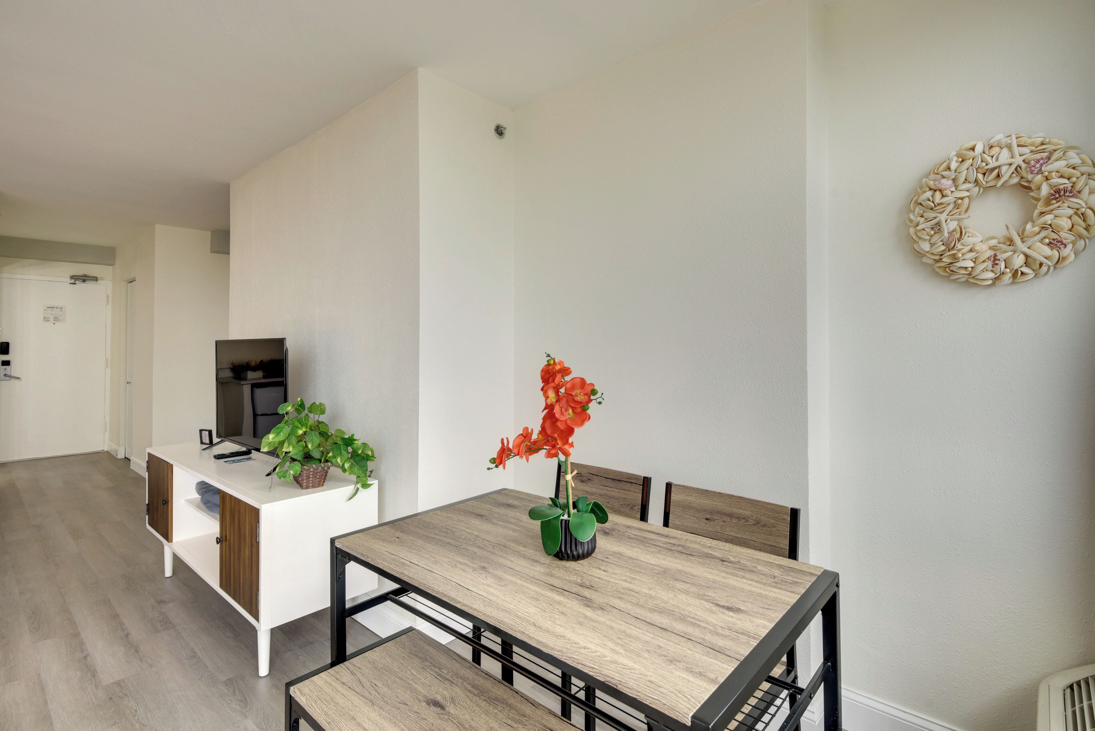 A modern dining area with a wooden table, chairs, a white cabinet, and a potted plant.