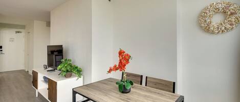 A modern dining area with a wooden table, chairs, a white cabinet, and a potted plant.