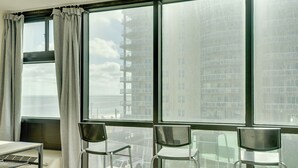A hotel room with a large window, a table, and two chairs. - Oceanfront Studio Amazing Beach Views Pool (Daytona Beach Shores)