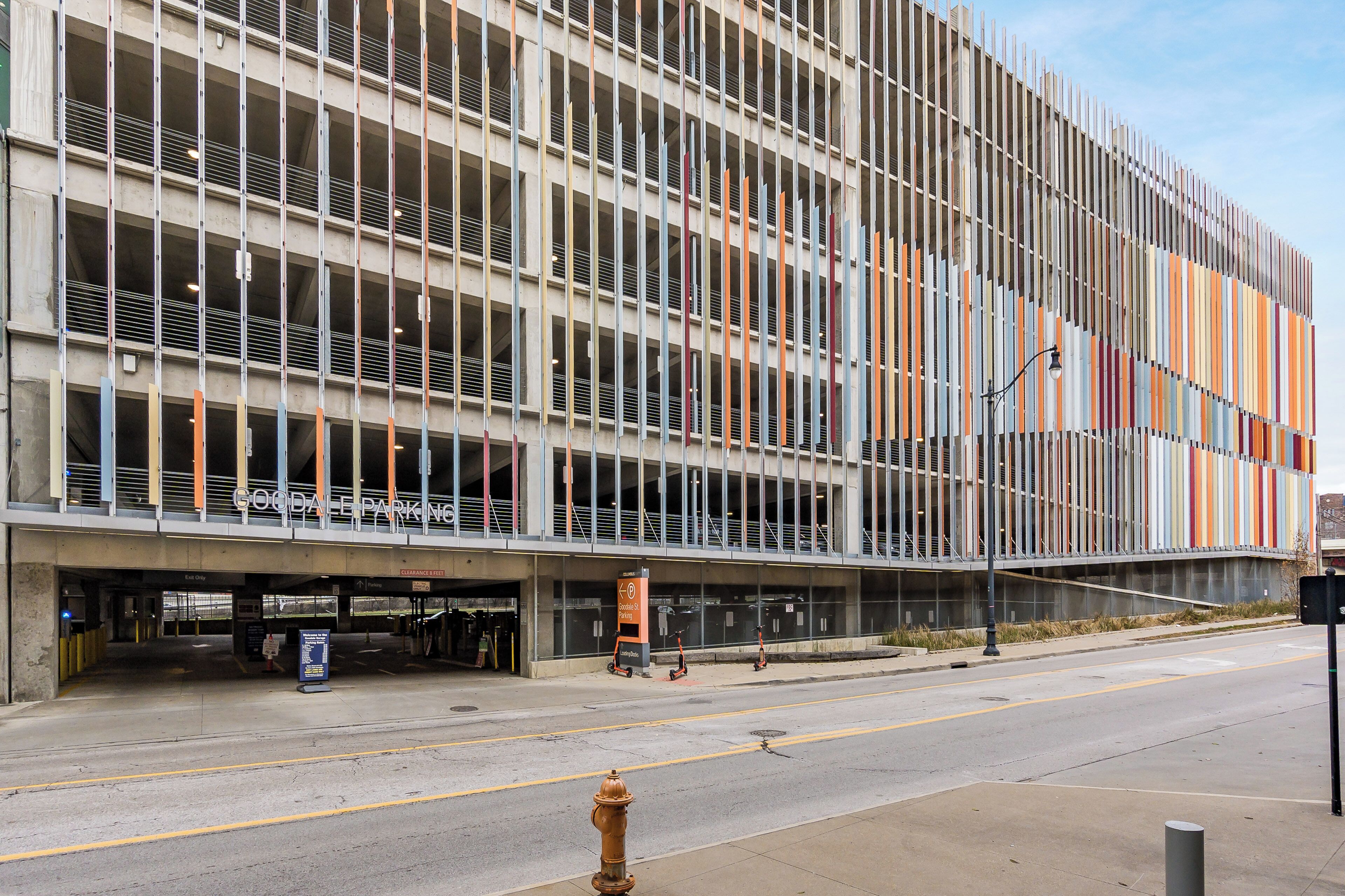 A modern building with a grid-like facade, a covered parking area, and a clear sky.