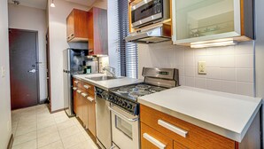 A modern kitchen with a stove, microwave, and oven. There is a sink and wooden cabinets.