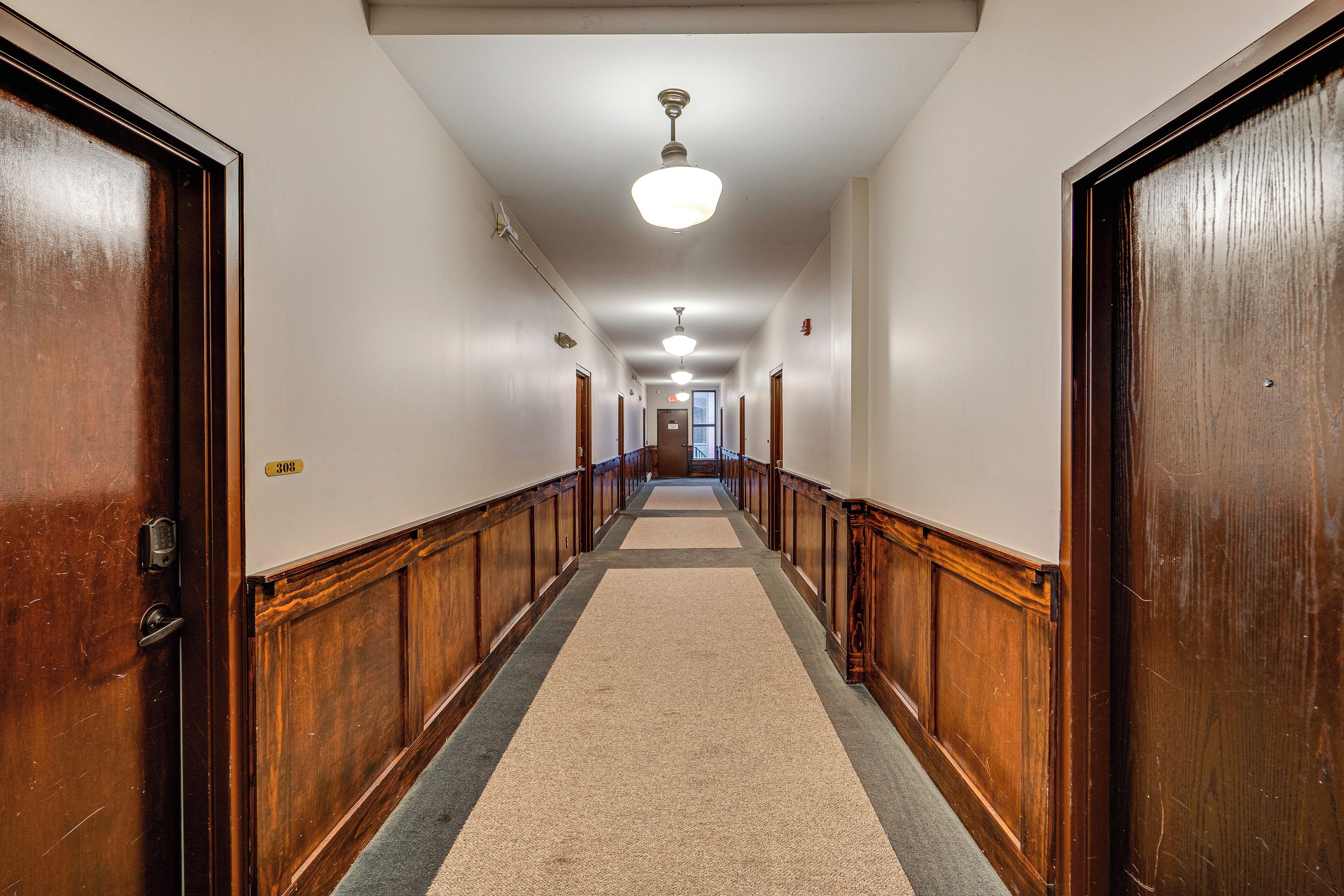 A hallway with wooden doors, a carpeted floor, and a ceiling light.