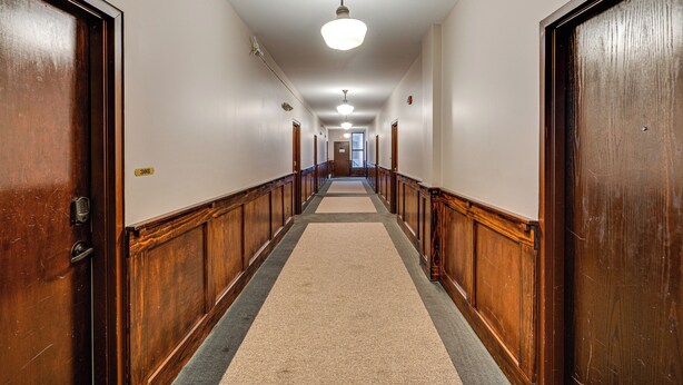 A hallway with wooden doors, a carpeted floor, and a ceiling light.