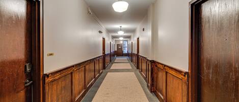 A hallway with wooden doors, a carpeted floor, and a ceiling light.