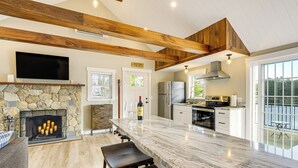 Una cocina espaciosa con chimenea de piedra, vigas de madera y una isla grande.