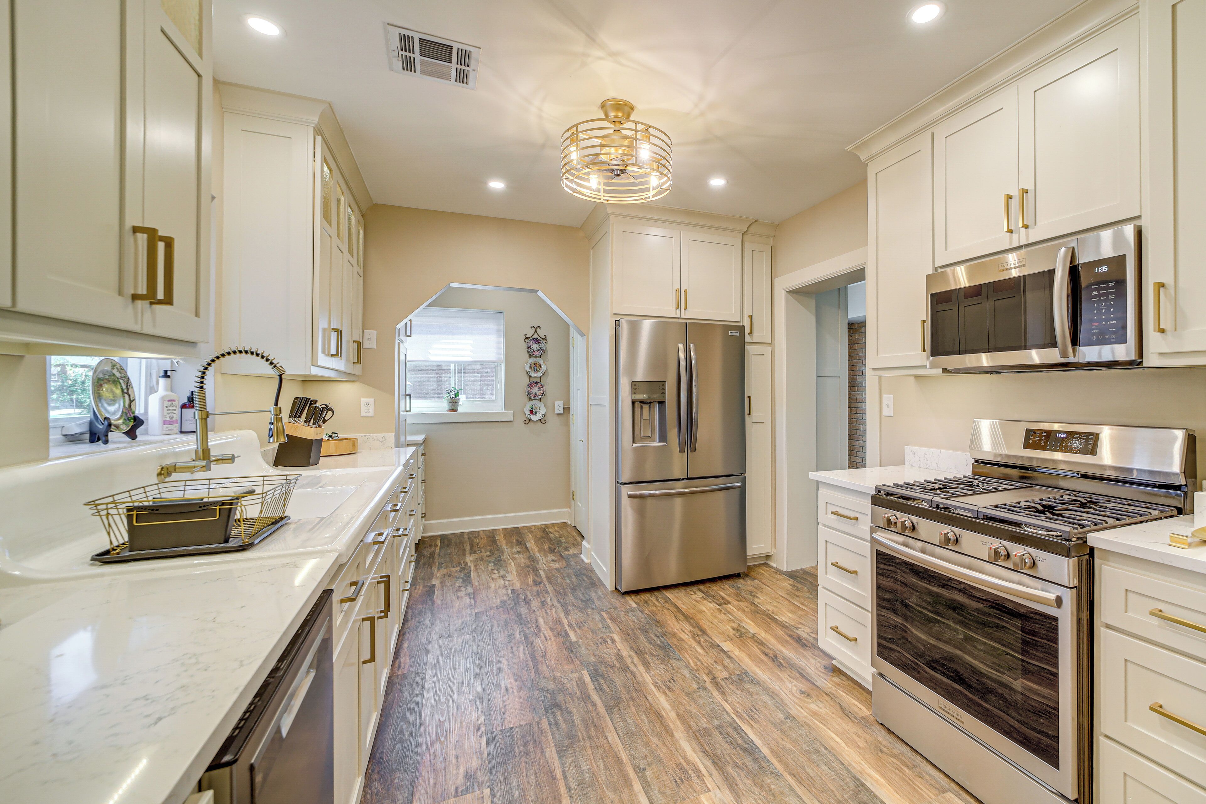 A modern kitchen with stainless steel appliances, white cabinetry, and a wooden floor.
