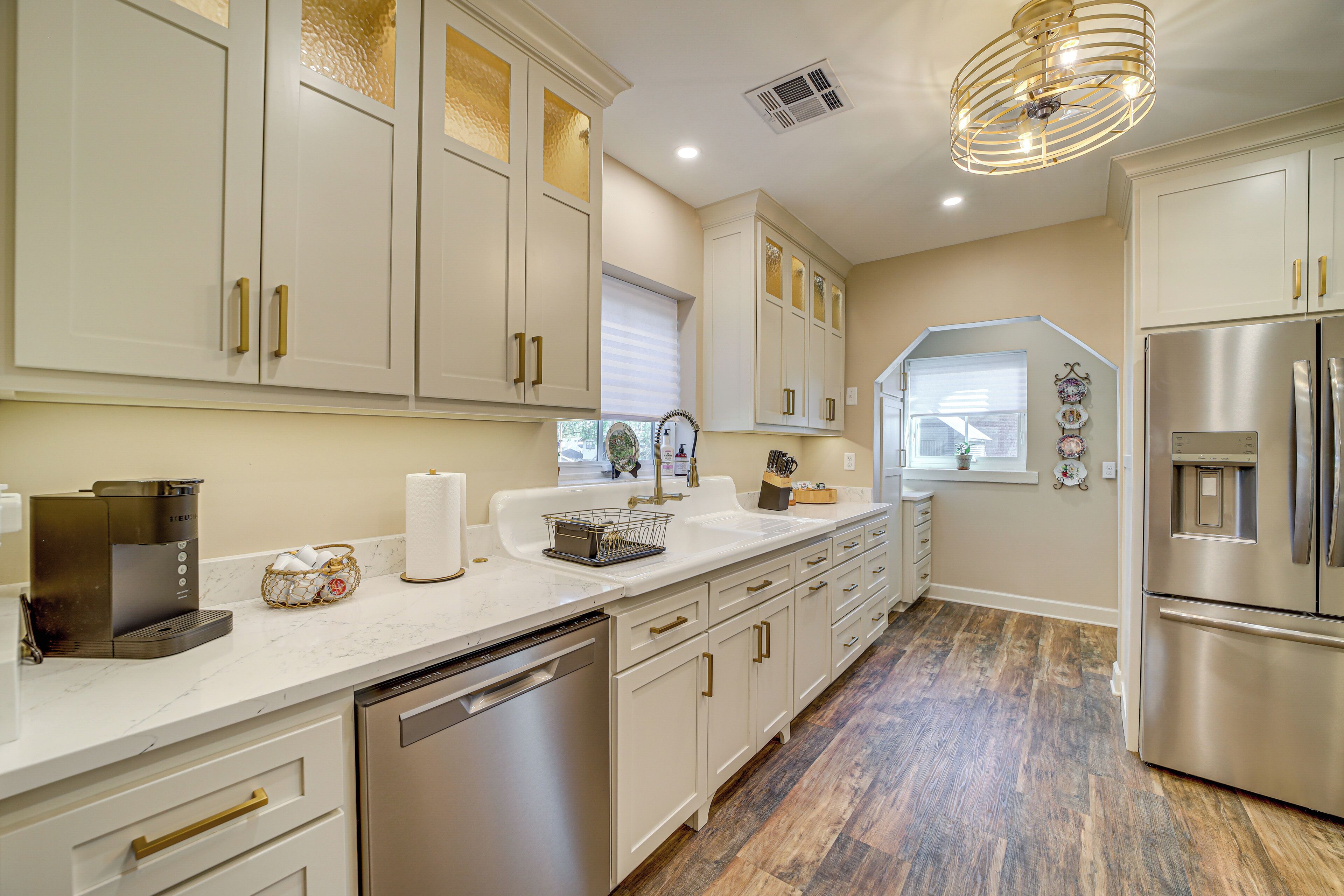A modern kitchen with white cabinetry, stainless steel appliances, and a marble countertop.