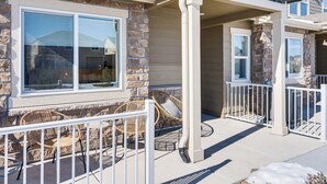 A house with a stone facade, large windows, and a covered patio with wicker furniture. - 10 Mi to Fort Carson: Newly Built Townhome! (Colorado Springs)