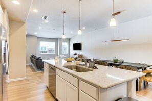 A modern kitchen with a central island, stainless steel appliances, and pendant lighting. - 10 Mi to Fort Carson: Newly Built Townhome! (Colorado Springs)
