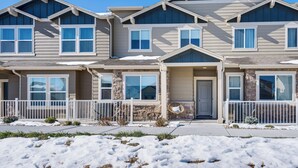 A multi-story residential building with a stone facade, multiple windows, and a front porch with chairs. - 10 Mi to Fort Carson: Newly Built Townhome! (Colorado Springs)