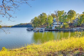 A lakeside property with a dock, boats, and a large house surrounded by trees. - Lake Hamilton Escape w/ Boardwalk & Boat Dock! (Royal)