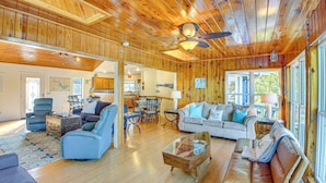A spacious living area with a wooden ceiling, a dining table, and a sofa.