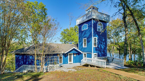 A blue building with a tower, a porch, and a staircase.