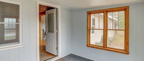 A hallway with a wooden-framed window, a door leading to another room, and a carpeted floor.