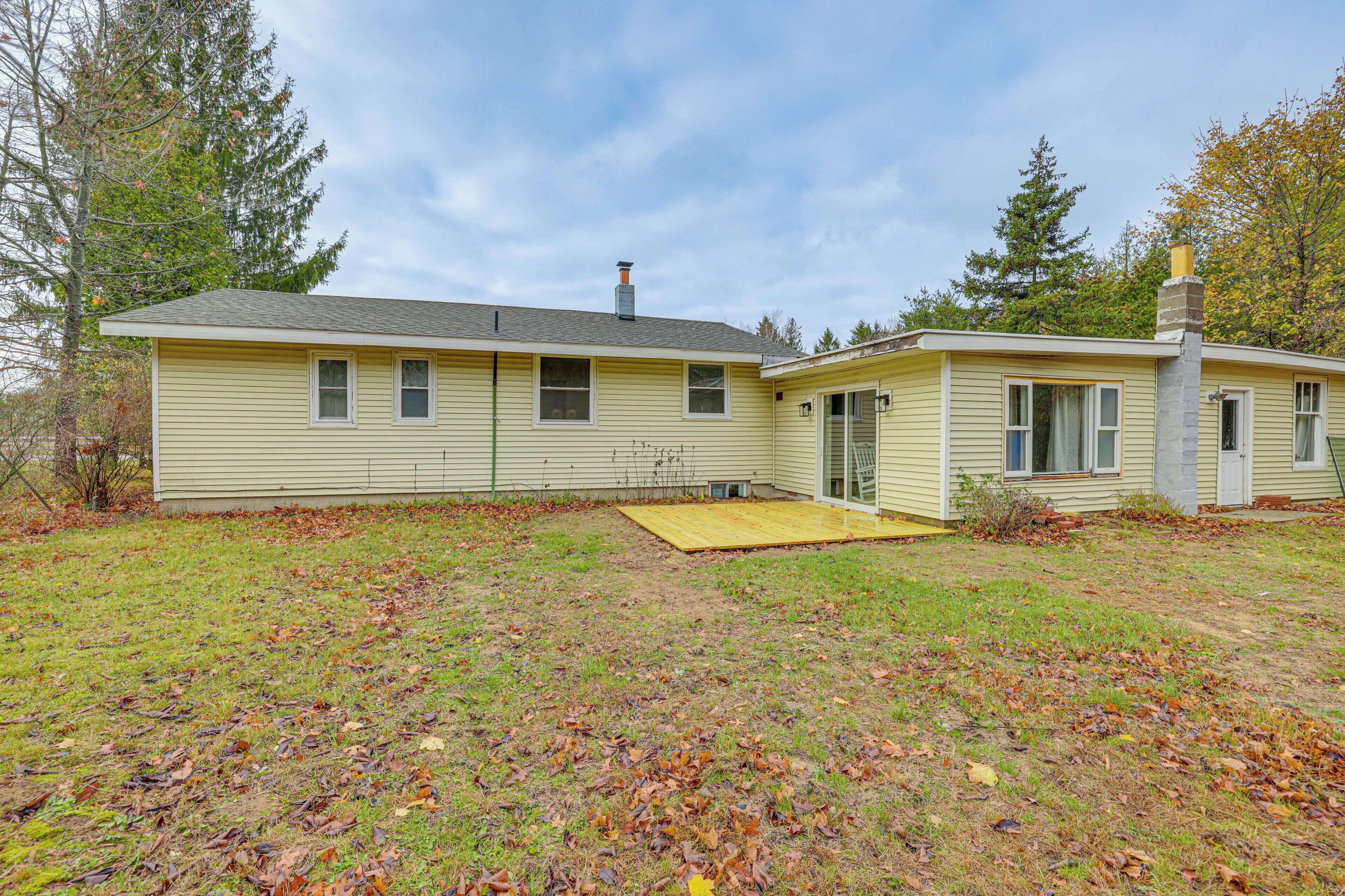 A two-story house with a front yard, a wooden deck, and a chimney.