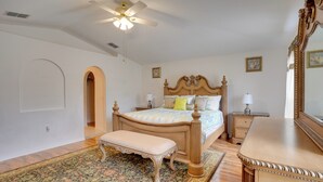 Ein Schlafzimmer mit einem hölzernen Bett, einer Bank, einem Nachttisch, einer Kommode und einem Deckenventilator.