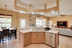 A modern kitchen with a central island, built-in appliances, and a dining area with chairs. - 9 Mi to Downtown Fort Myers: Home w/ Lanai + Grill (Cape Coral)