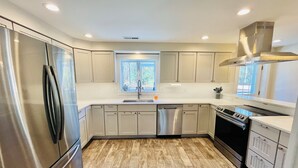 Una cocina moderna con electrodomésticos de acero inoxidable, suelo de madera clara y un ventanal que proporciona luz natural.