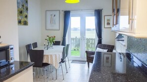 A kitchen with a dining table, chairs, a microwave, and a hanging light fixture. - Our Story Cottage (Alnwick)