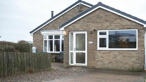 A two-story brick house with a pitched roof, a front door, and a window. - Our Story Cottage (Alnwick)