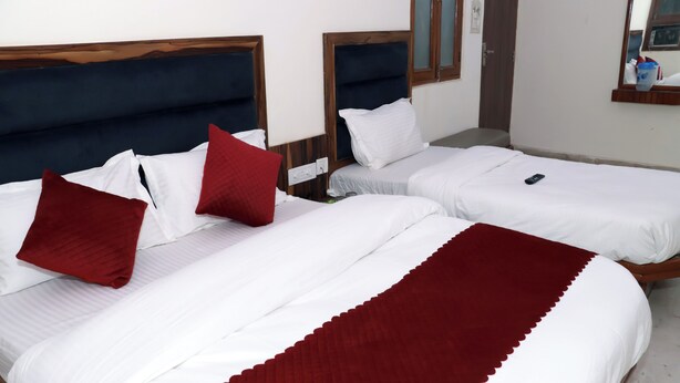 Habitación de hotel con dos camas, cada una con ropa blanca y almohadas rojas.