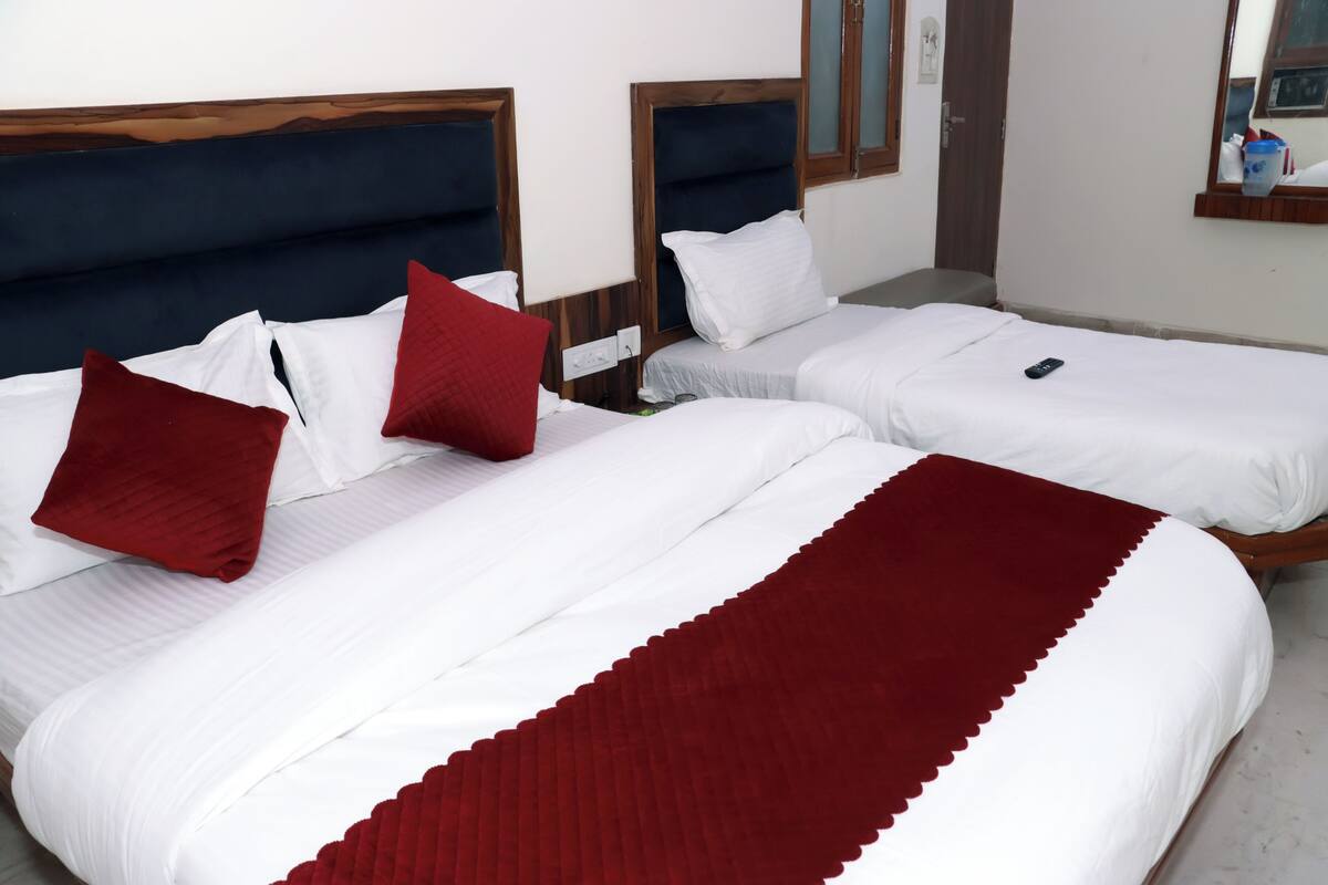 A hotel room with two beds, each with white bedding and red pillows.