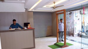 Un área de recepción con diseño moderno, que incluye un mostrador de recepción, un ventilador de techo y una puerta de cristal que da al exterior.