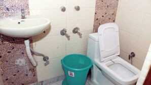 Un baño con lavamanos, inodoro y un cubo verde.