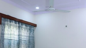 Un dormitorio con cama, ventilador de techo y ventana con cortinas.
