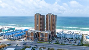 Un complejo hotelero frente al mar con varios edificios altos, una playa y un estacionamiento.