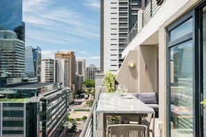 A high-rise building with a balcony featuring a table, chairs, and a bottle of wine. - Cape Town Deluxe City Apartment Hafen Views (Cape Town)